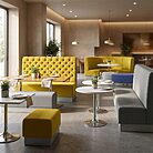 Espace de restauration moderne avec collection de banquettes Akaashi jaunes, grises et bleues à haut dossier pour restaurants, bars et espaces d’accueil