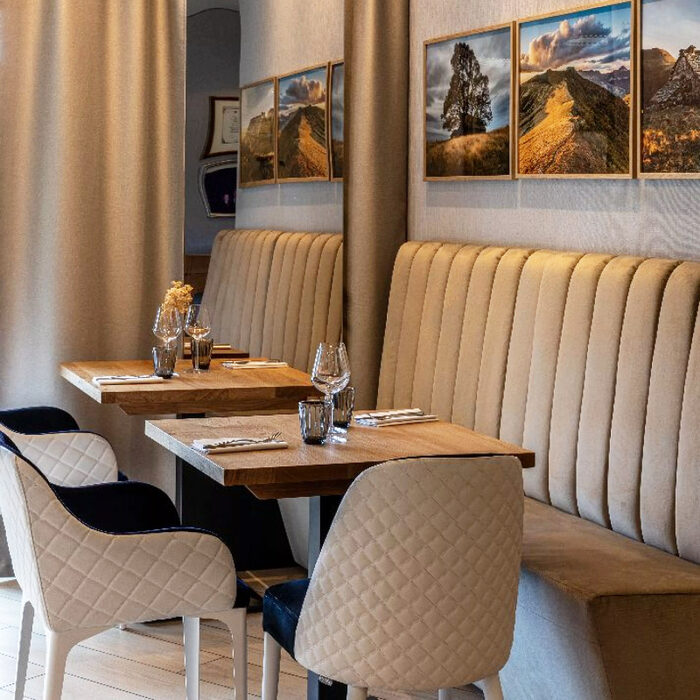 Banquettes droites taupe sur mesure le long du mur avec tables en bois massif et chaises capitonnées