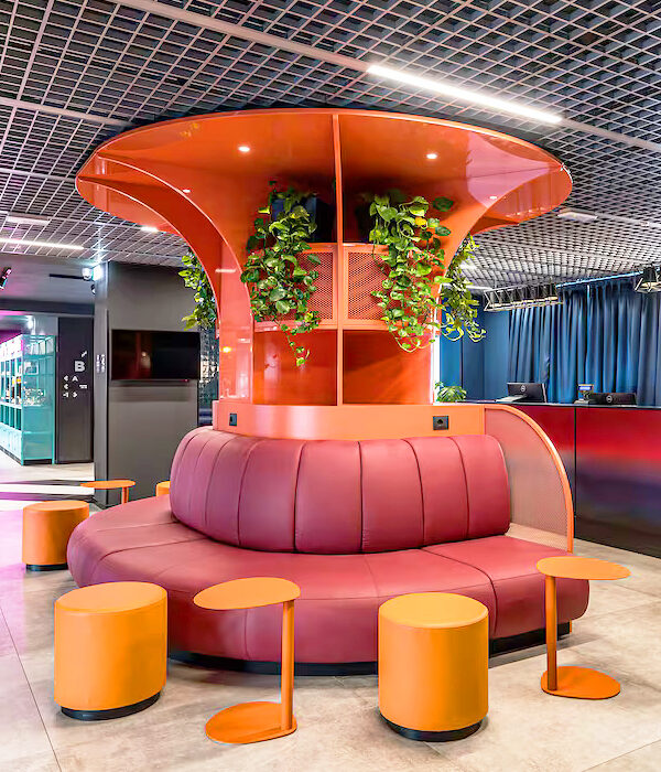 Banquette arrondie circulaire EPSILON en simili cuir orange autour d’une colonne design végétalisée dans un hall d’hôtel