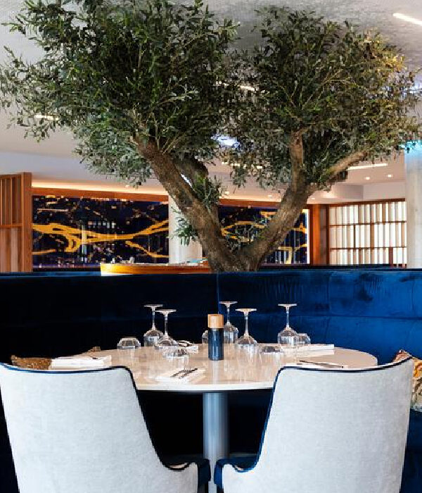 Banquette demi-lune haut dossier en velours bleu autour d’une table en marbre blanc dans un restaurant d’hôtel