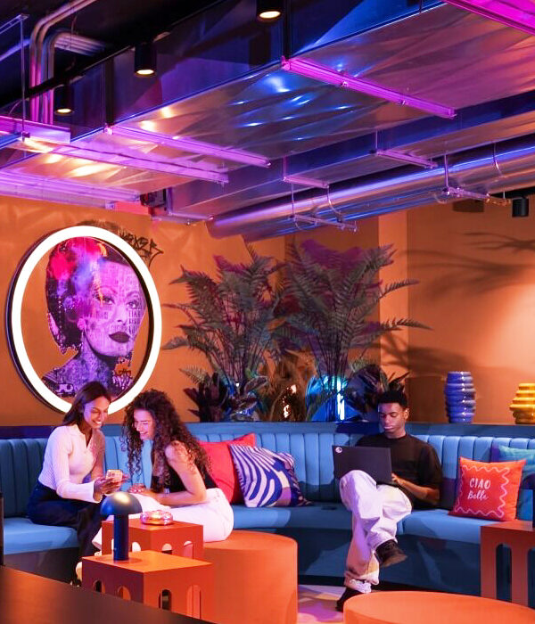 Banquette sur mesure en simili cuir bleu avec dossier capitonné le long d’un mur et poufs ronds orange dans un espace repos hôtel