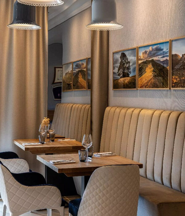 Banquette murale AOKO dans un restaurant d’hôtel à Salers avec tables carrées et fauteuils matelassés blanc et bleu marine