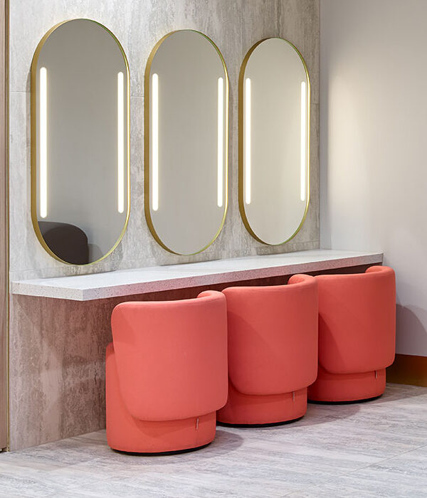 Trois fauteuils PACHA en simili cuir orange face à des miroirs ovales dans une zone maquillage de centre commercial