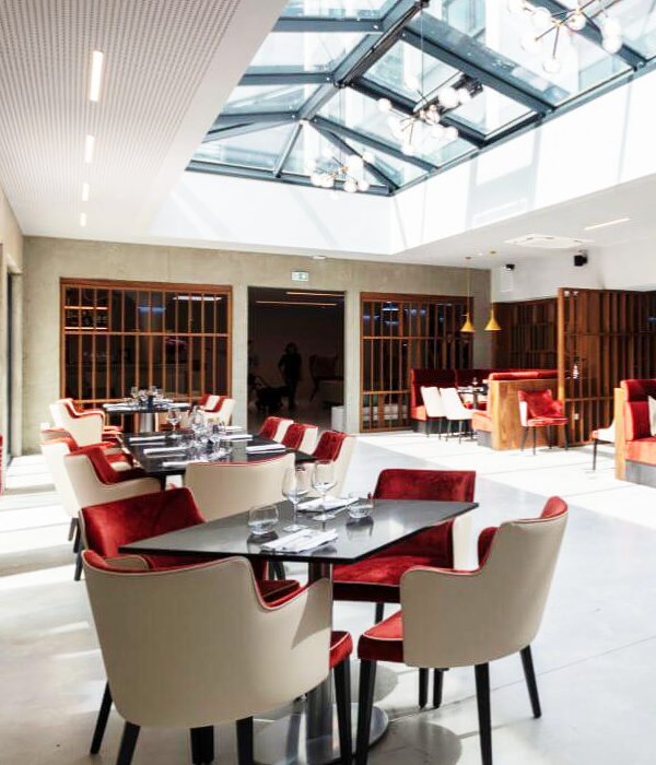 Ensemble fauteuils et table avec revêtement velours bicolore rouge et blanc dans un espace restaurant hôtelier