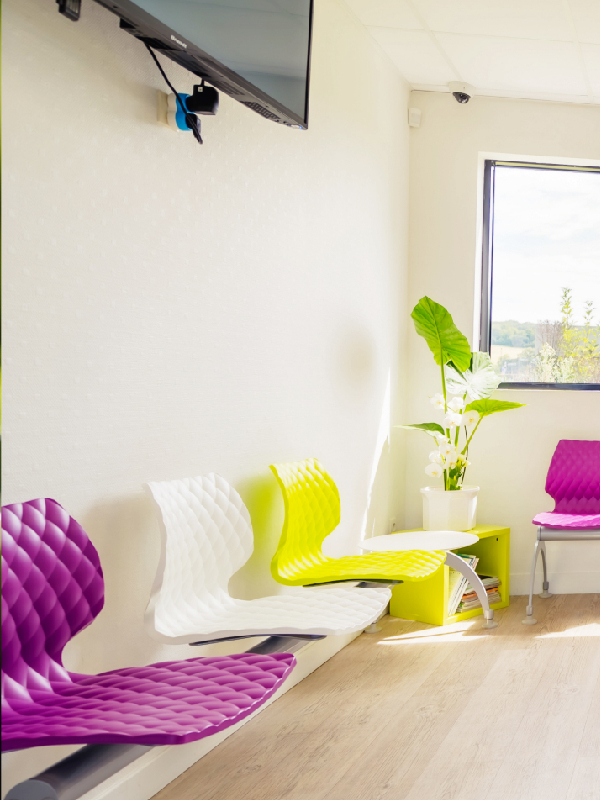 Zone TV dans une salle d’attente de cabinet dentaire avec banquette sur poutre DIAMS colorée et ambiance pop art adaptée aux enfants et adultes