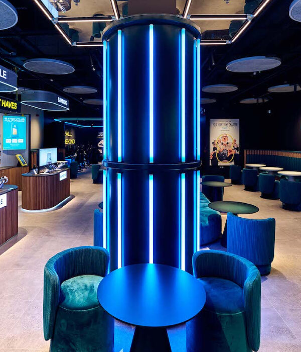 Zone centrale type bar avec deux fauteuils PACHA en velours bleu et dossier tissu dans un espace d’expérience immersif